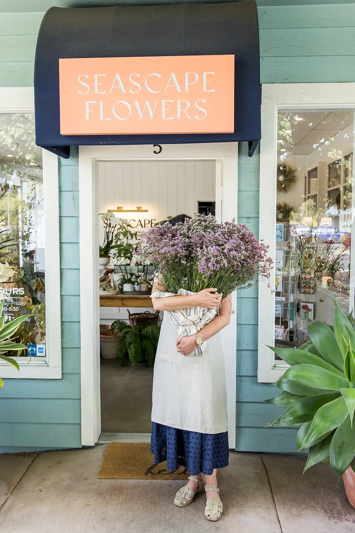 Florist standing with lavender bouquet outside Seascape Flowers in Aptos CA