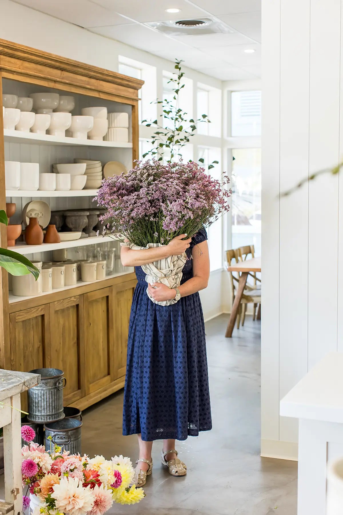Florist holding large flower bouquet inside Seascape Flowers Aptos floral shop